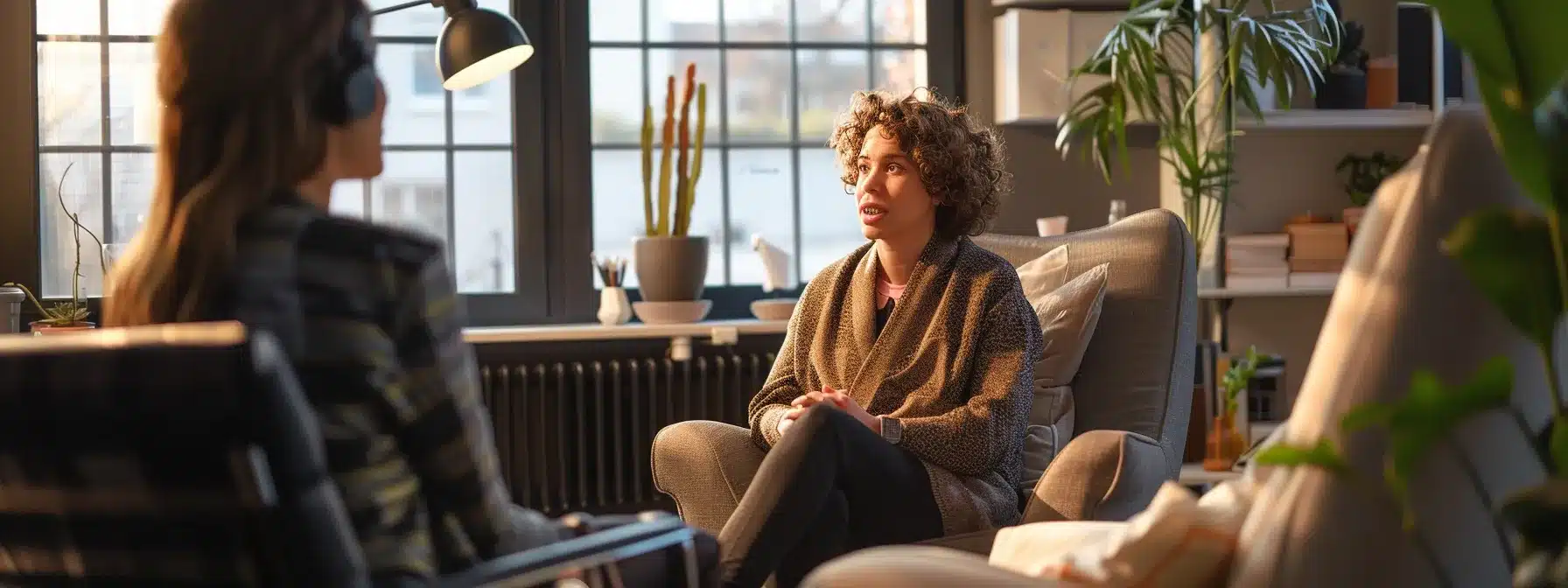 a woman sitting in a cozy chair, talking to a therapist in a warmly lit office.