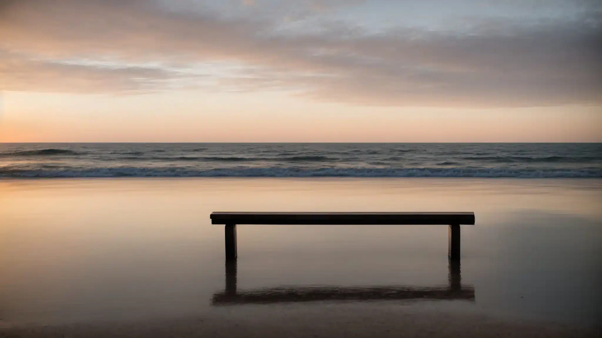 a sunrise breaks over an empty bench facing a calm sea, symbolizing a new beginning and the quiet contemplation of renewal amidst uncertainty.